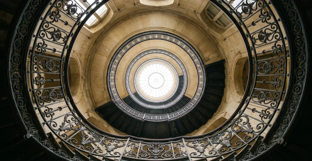 Escalier en colonne ascendant vers une verrière lumineuse, symbolisant la progression organique d'un site vers la premiere page de Google sans backlink externe